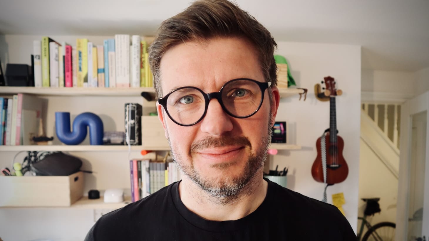 Iain Broome selfie, wearing glasses, a black t-shirt and slightly self-conscious smile. 